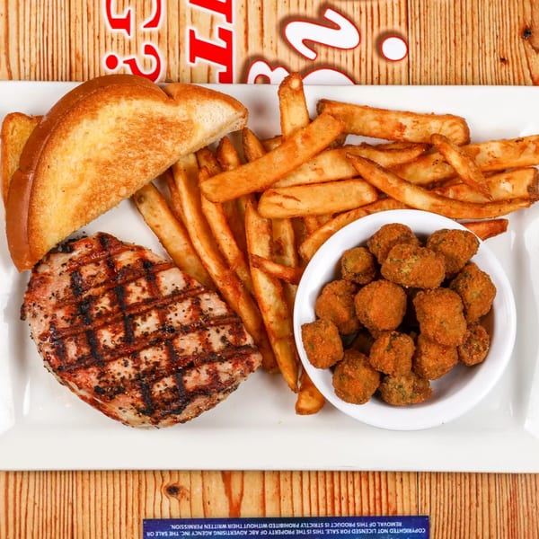 Grilled pork chop, golden fries, toasted bread, and a bowl of fried mushrooms on a white plate.